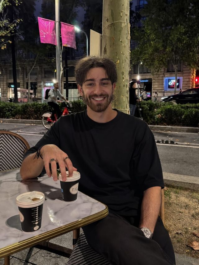 Hugo Pilard, souriant, assis à une terrasse de café le soir.
